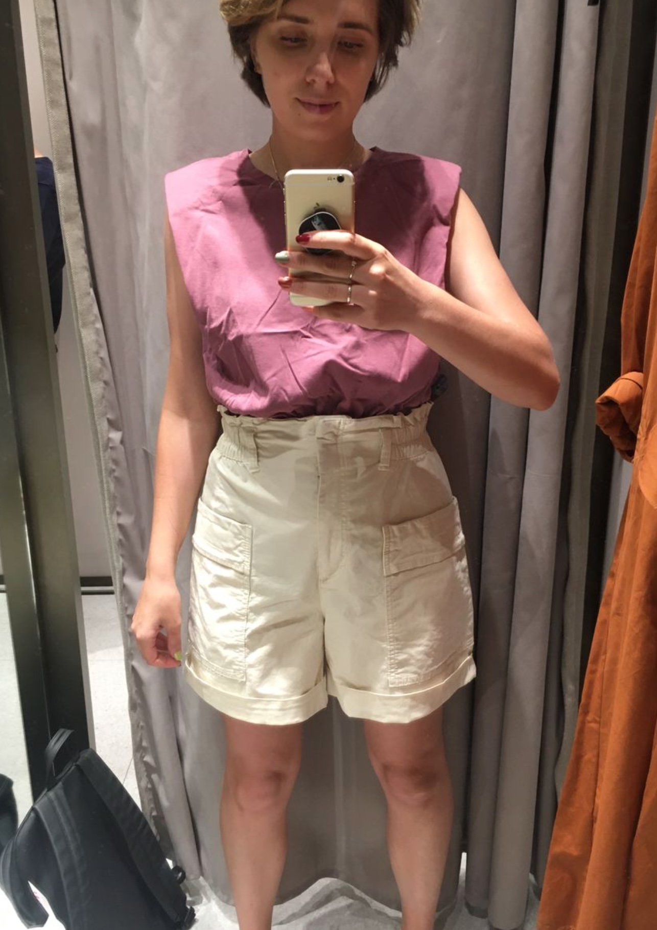 Before styling: fitting-room outfit with pink top and cream shorts