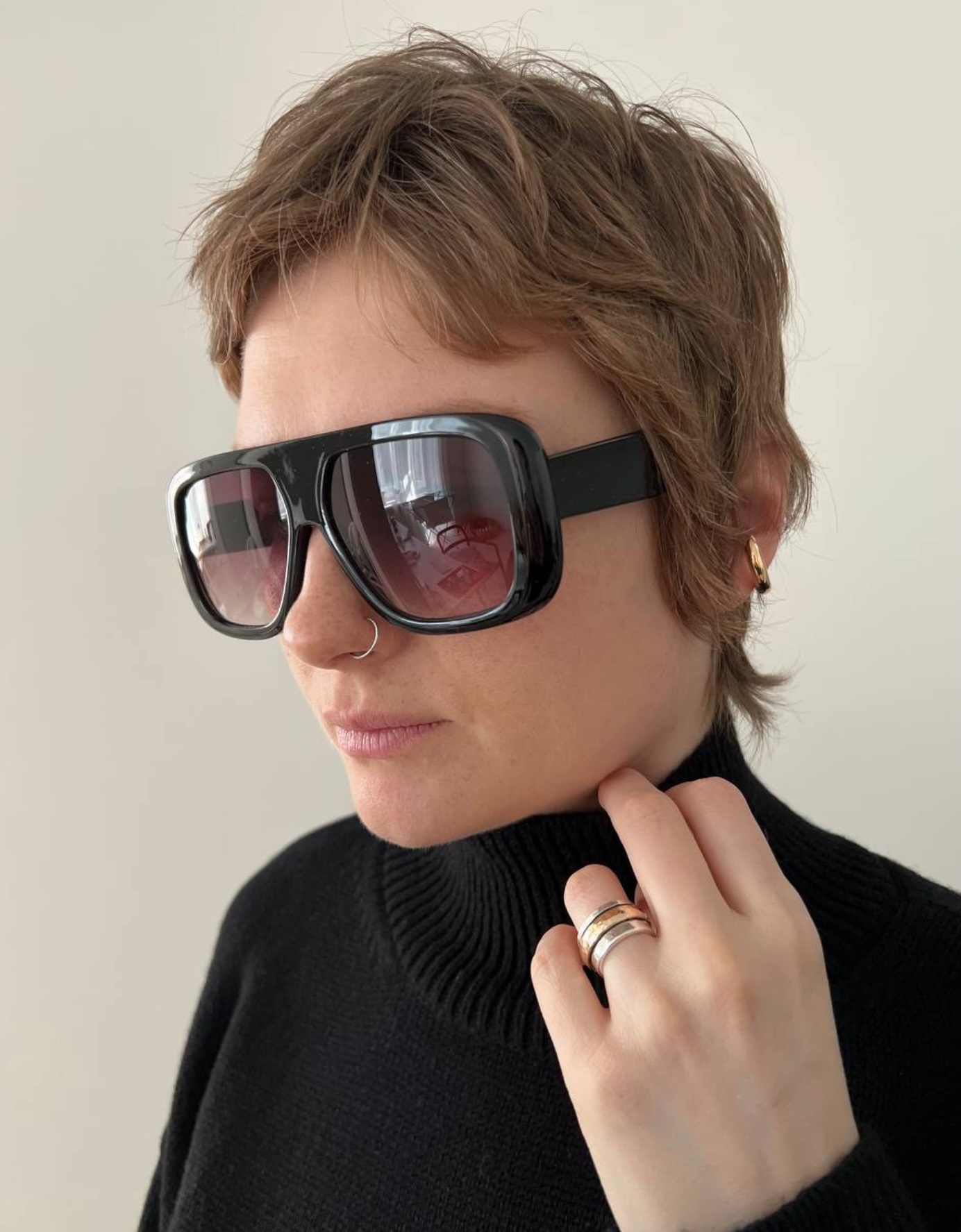 After styling: close-up portrait with black sunglasses, earrings, softer hair, and black knitwear
