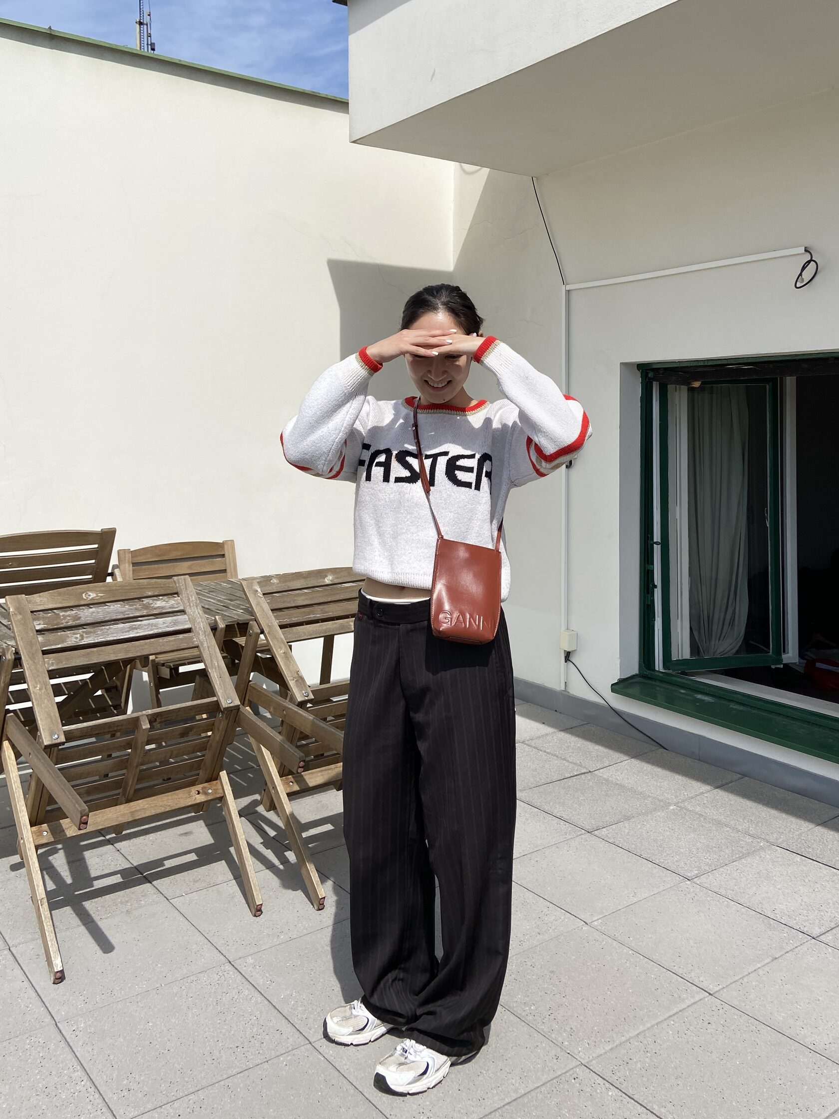 Outdoor outfit with white sweater, dark trousers, and small leather bag